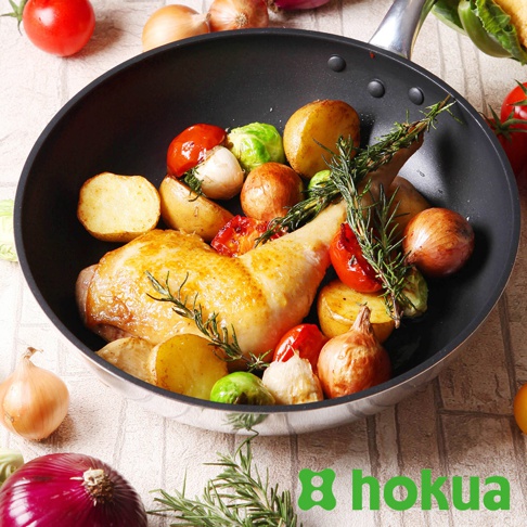 平底鍋中烹調著金黃烤雞腿，配以馬鈴薯塊、小番茄、抱子甘藍和洋蔥，點綴迷迭香。
