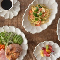 淺色陶瓷橢圓料理盤，邊緣呈花瓣狀，盤中盛有義大利麵、煙燻鮭魚、蔬菜、麵包、水果等食物。