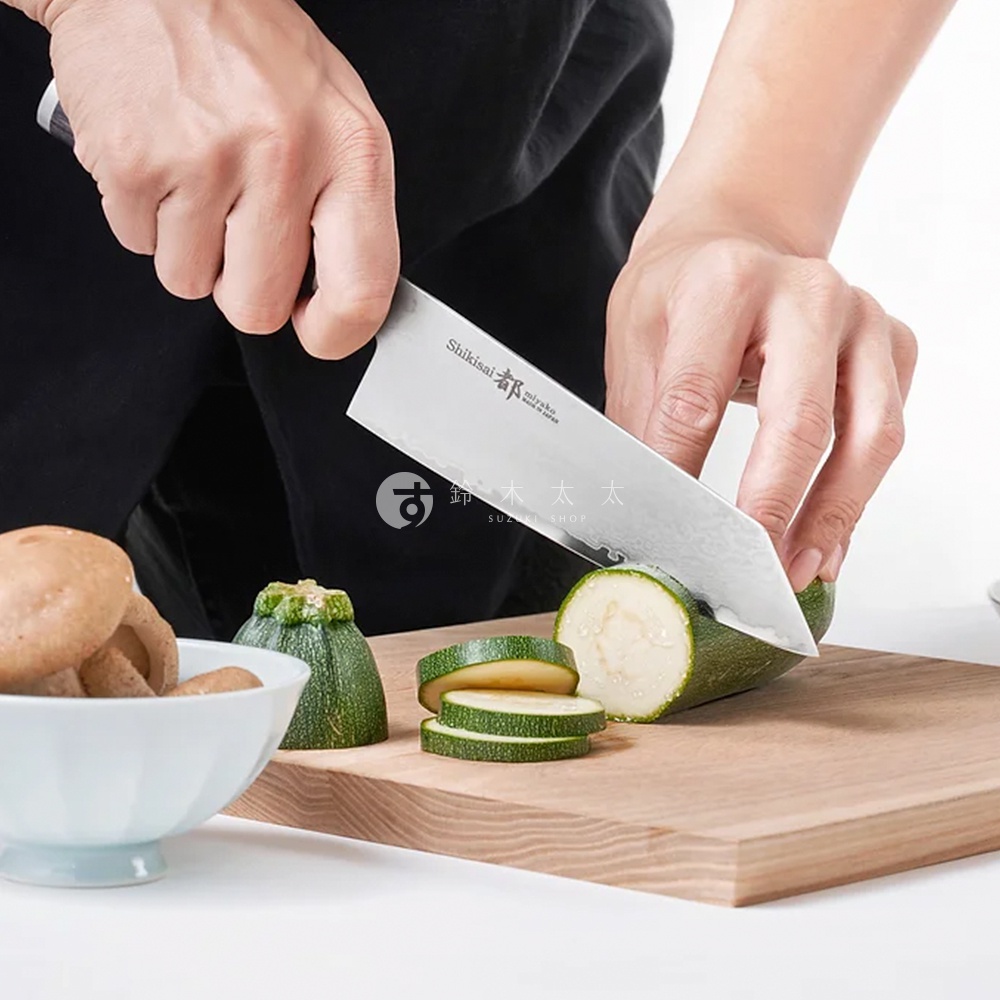 Shikisai Miyako 文化刀，鋒利的不鏽鋼刀刃，正在切片綠色櫛瓜，旁邊有香菇和一個小綠色蔬菜。