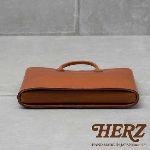 職人手作咖啡色薄型皮革公事包，設有提把，簡潔設計，適合商務場合。