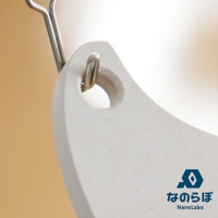 淺灰色珪藻土防潮塊，表面帶有細微顆粒，一端有圓孔，穿有金屬掛環。