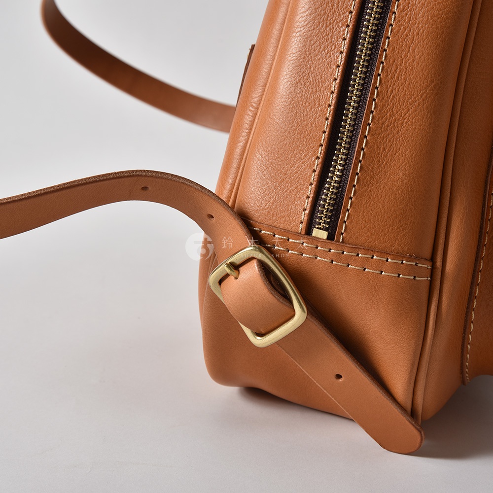 職人手作迷你後背包，採用棕褐色皮革，帶有立體口袋設計，裝飾著金屬拉鍊和皮帶扣，肩帶可調節。