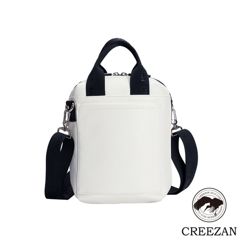 高爾夫方形側背包，採用紋理皮革材質，主體為白色，搭配黑色織帶提把與可拆卸肩帶，肩帶上印有品牌名稱。