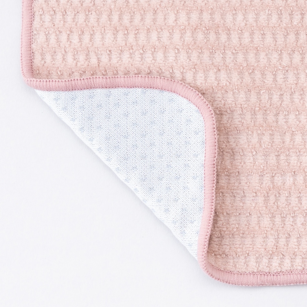 粉色涼感毛巾，表面為網狀織紋，邊緣為粉色滾邊。毛巾一角翻開，露出內層白色網狀材質，點綴有藍色小圓點。