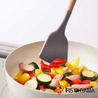 灰色矽膠鍋鏟正在翻炒鍋中的香腸、櫛瓜、紅黃甜椒等食材，鍋鏟手柄為木質。