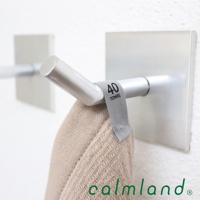 一張特寫照片，展示了一個銀色金屬毛巾架，上面掛著一條米色長方巾。毛巾巾上有一個灰色標籤，上面印有「40 TOWEL」字樣。