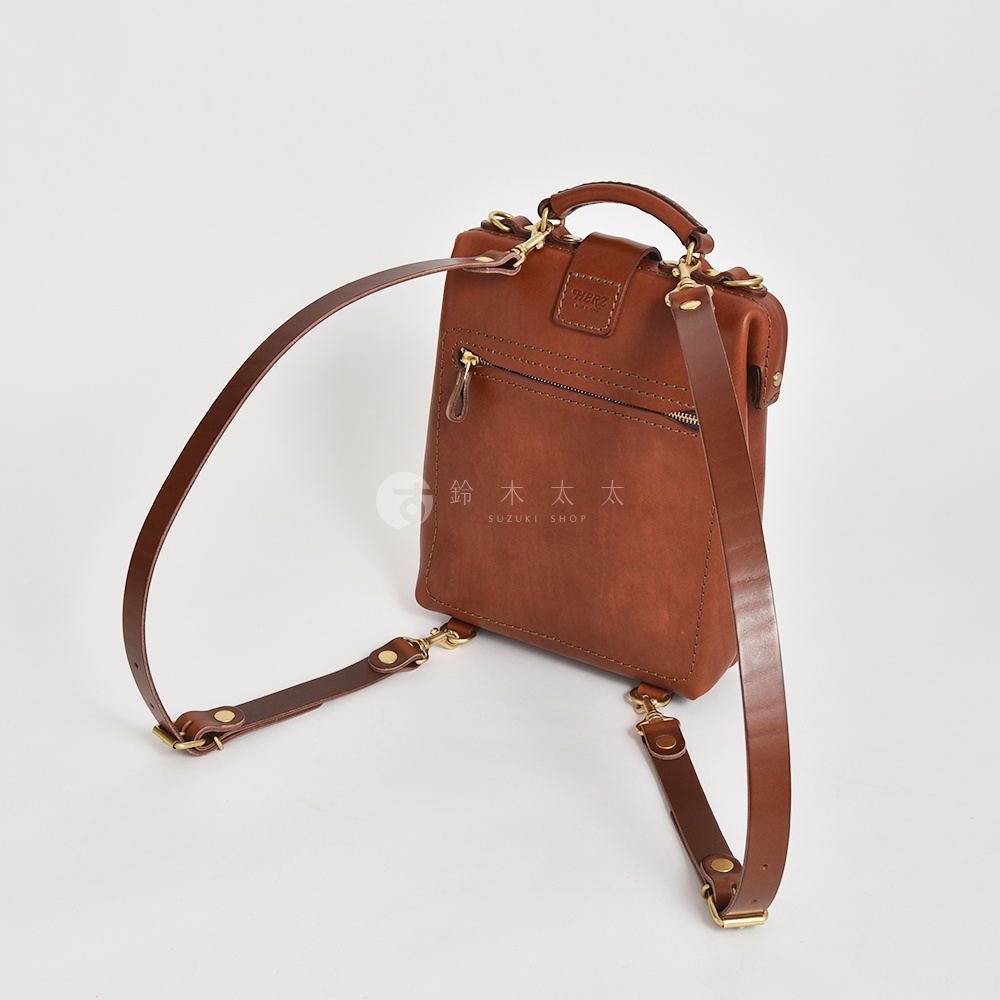 職人手作皮革迷你軟皮杜勒斯包，呈現溫潤的棕色調，以精緻的皮革材質製作，搭配黃銅色金屬扣件，設計簡約實用。