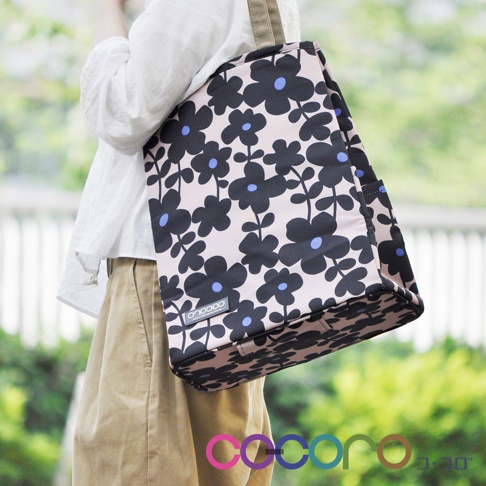 粉紅色提袋購物車，印有黑色花朵圖案，花朵中心為藍色。提袋為方形，側面可見提帶。