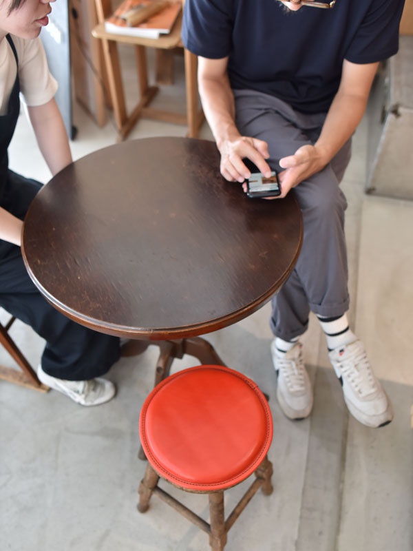 職人手作皮革圓形坐墊，鮮紅色皮革表面，搭配仿舊木質三腳凳架，適合居家或咖啡廳使用。