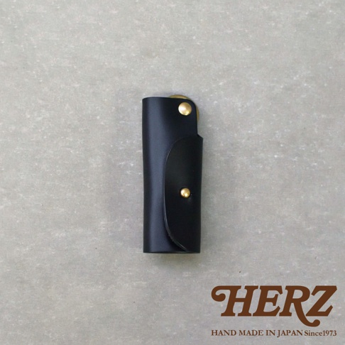 黑色皮革鑰匙套，採用職人手作工藝，正面有兩個黃銅色金屬按鈕，可收納鑰匙。