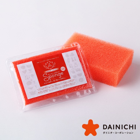 兩塊橙色海綿，一塊裝在透明塑膠包裝內，印有日文產品資訊和圖案，另一塊則獨立擺放，材質為細緻的發泡海綿。