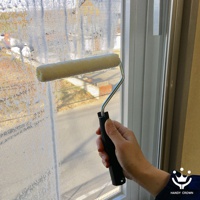 手持黑色握柄的省力紗窗刷，其乳白色滾輪正在清潔附有污漬的紗窗。