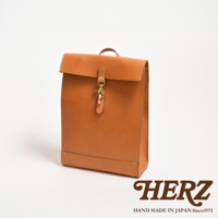 職人手作皮革紙袋風後背包，採用光滑棕色皮革製成，配有黃銅扣環和縫線細節，風格簡約。