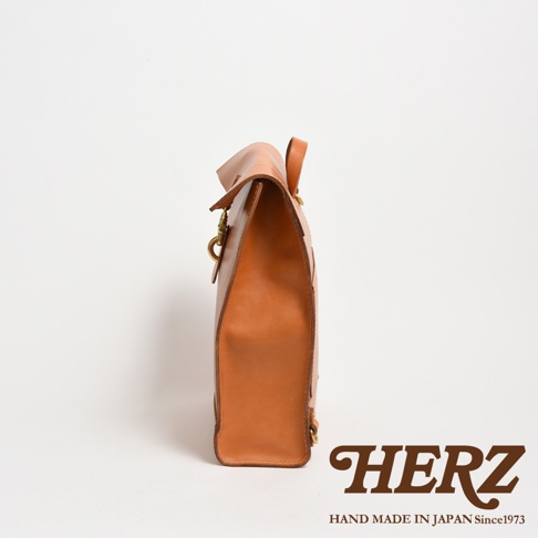 職人手作皮革紙袋風後背包，側邊視角，淺棕色皮革，配有金屬扣環。