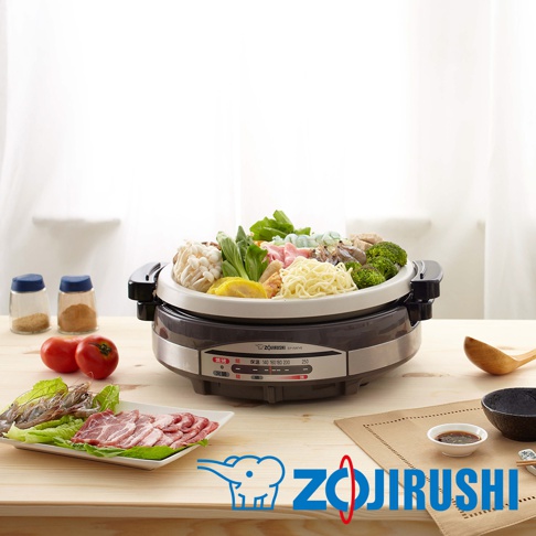 土鍋風鐵板萬用鍋 EP-RAF45，鍋內裝有豐富的火鍋食材，包含蔬菜、菇類、肉片、海鮮及麵條。鍋體為深灰色，設有溫度顯示面板，搭配木質桌面和餐具，整體呈現溫馨的用餐氛圍。