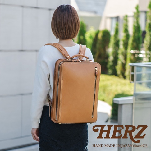 咖啡色皮革商務電腦後背包，方形設計，正面有兩條垂直拉鍊，頂部有提把，肩帶可調節。