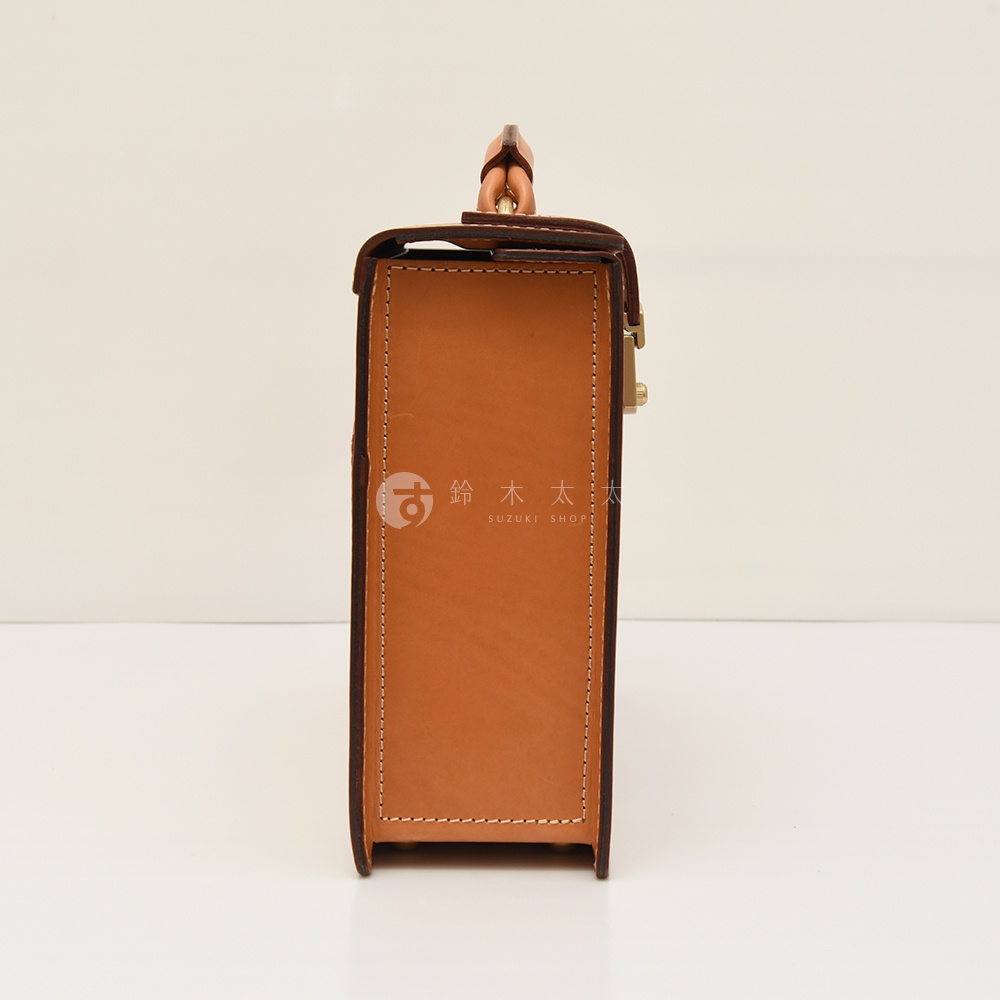 職人手作皮革機師箱BC-31，側面視角，展示淺棕色皮革材質，車線清晰，配有金色金屬鎖扣及提把。