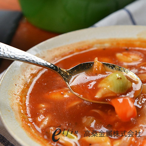 日製錘目紋不鏽鋼餐匙，銀色，表面帶有Hammered紋理，勺頭盛有紅色湯品及蔬菜。