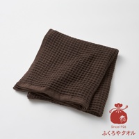 深棕色格子紋理的毛巾，一角疊起，呈現柔軟質感