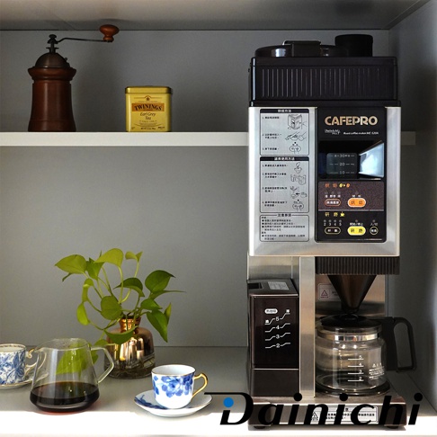 銀色與黑色調的自動生豆烘焙咖啡機 MC-520A，機身前方印有中日文說明與操作指示，下方是玻璃咖啡壺與研磨刻度顯示。