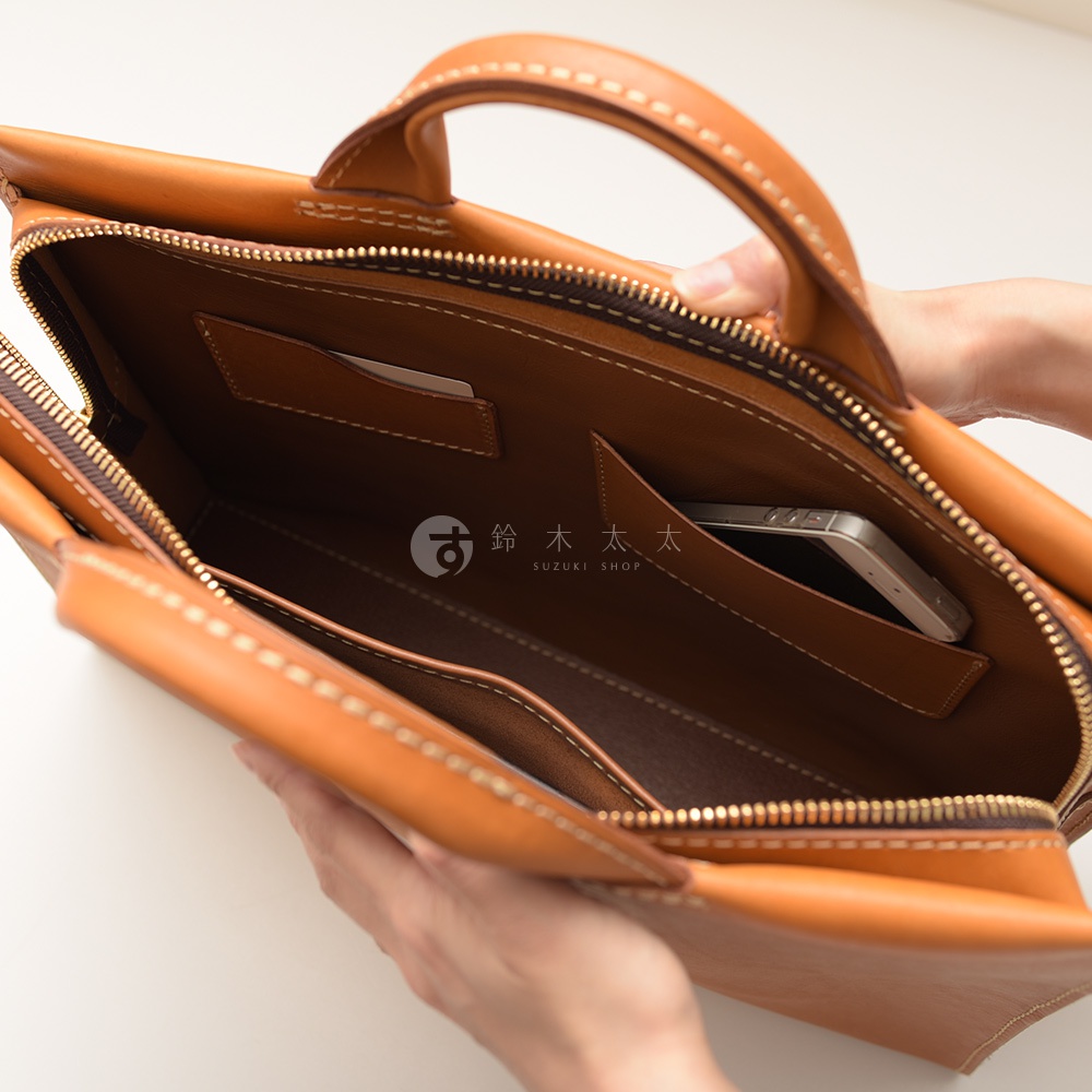 日本HERZ職人手作皮革公事包，焦糖色皮革，特寫包內構造，可見手機放置在內袋。