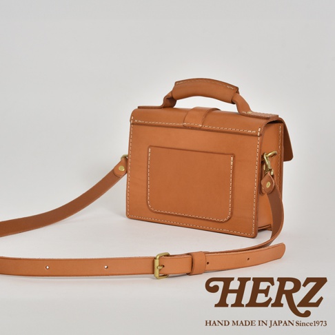 職人手作皮革經典混合風迷你單肩包，採用天然皮革材質，呈現溫潤的焦糖棕色。包款設計簡約，配有手提握把、可調節長度的肩帶及金屬扣環，正面有方形外袋，縫線清晰。