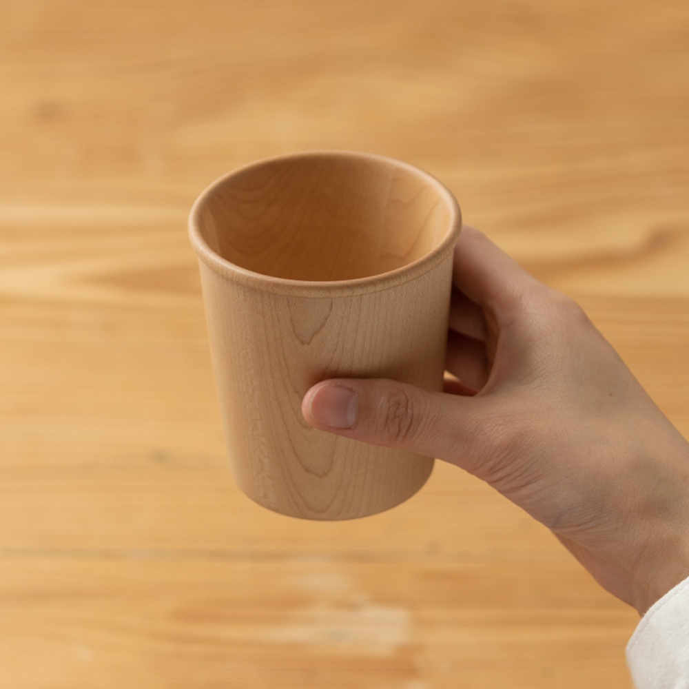手持楓木寬口杯，杯身呈現淺木色，帶有細膩的自然紋理。