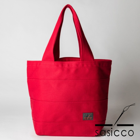 紅色三河木綿刺子織大容量托特包，具有明顯的菱形紋理和橫向車縫線，配有兩條寬肩帶，包身底部有黑色標籤，印有品牌標誌。