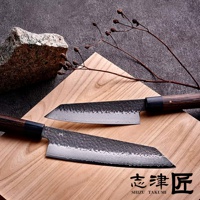 玄 / Bunka 文化刀19cm，兩把錘紋鋼刀刃，深棕色木質手柄，置於木質砧板上，背景為灰色石材與乾燥枝條。
