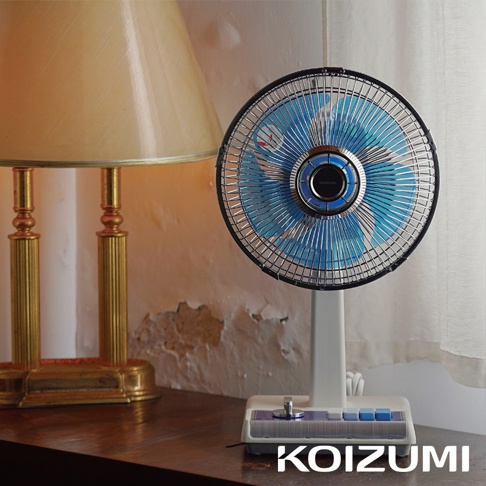 復古電風扇，10吋，藍色扇葉，黑色網罩，白色扇身，配有藍色與白色按鈕的底座，放置於木質檯面上。