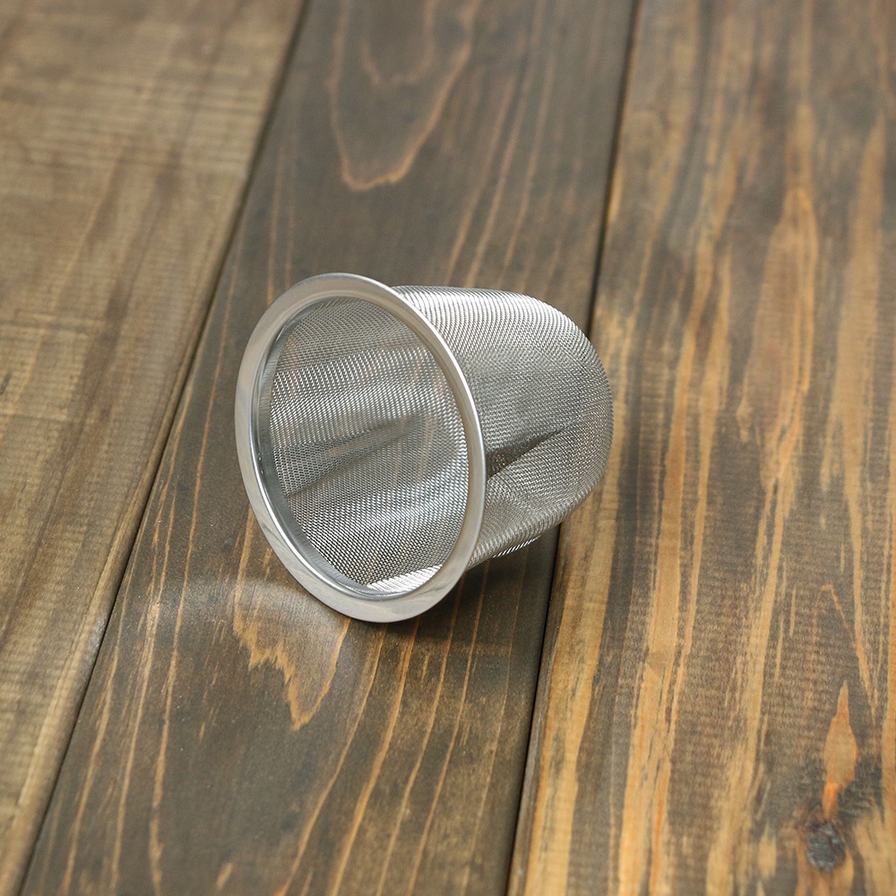 一個銀色不鏽鋼濾網，帶有細密的網孔，置於深棕色木紋背景上。