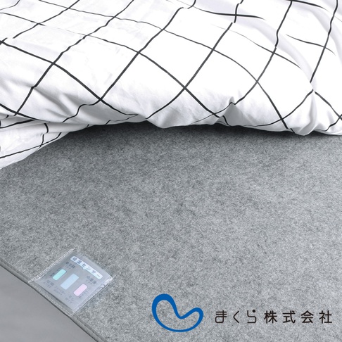 淺灰色備長炭防潮床墊，表面鋪有白色格紋床單，左下角有濕度感測器標籤。