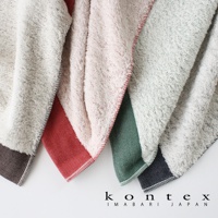 三條HERRINGBONE今治長纖有機棉斜紋浴巾，分別呈現米白色、淺粉色及淺灰色，並在底部飾有深棕色、紅色及綠色斜紋織帶，材質柔軟蓬鬆。