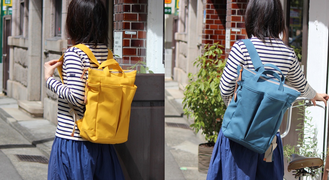 高島帆布製後背包，左圖為亮黃色，右圖為藍綠色，兩款均有外部口袋和頂部提把，帆布材質。