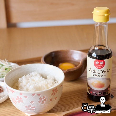 金笛雞蛋拌飯專用醬油 (150ml) 玻璃瓶裝，瓶蓋為黃色，標籤為米色，印有紅色金笛標誌及日文說明。旁有裝有白飯的櫻花圖案碗，以及裝有生雞蛋的陶碗。