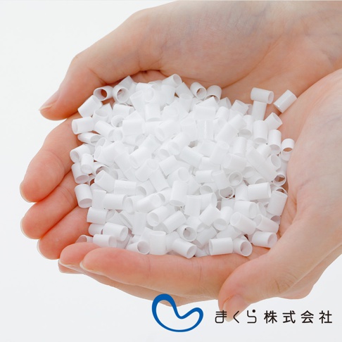 雙手捧著大量白色、圓柱狀的填充物，材質看起來是塑膠或類似的合成材料，這些填充物狀似細小的管狀顆粒，用於調節枕頭的軟硬度。