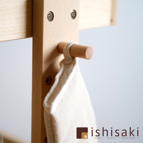 木質收納推車的細節，展示了淺木色木製結構、圓形木掛鉤，以及懸掛著的米白色布袋。