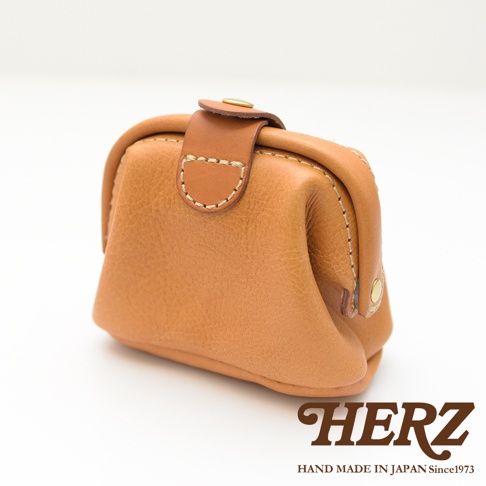 棕色皮革製作的圓潤口金化妝包，有著細緻的縫線與金屬釦，設計簡約，適合隨身攜帶。