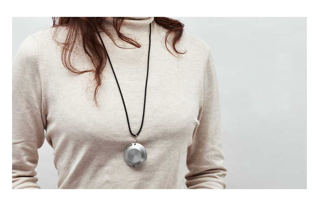 一名女性佩戴著銀色金屬材質的圓形吊墜，吊墜透過一條黑色細繩懸掛在頸部，吊墜表面有紋理設計。