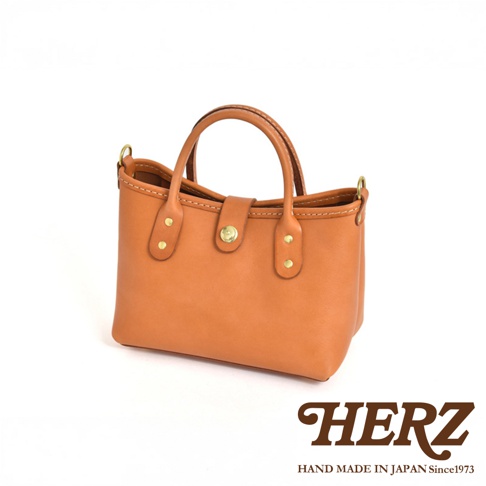 職人手作迷你托特包，天然皮革製成，呈現溫潤的焦糖棕色。包款設計簡潔，配有雙提把及金屬釦，展現質感。