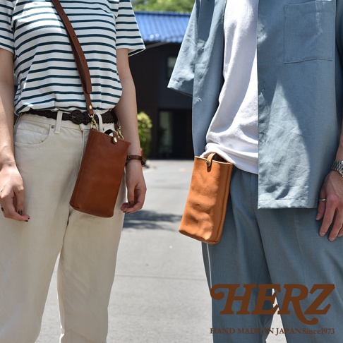 兩款棕色皮革製手機包，一款斜挎於女性身上，另一款夾於男性褲側，展現簡約實用的設計。