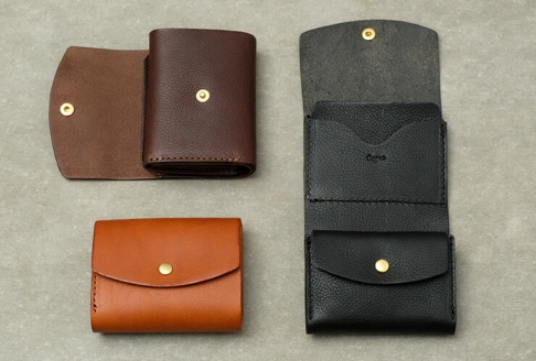 職人手作皮革Organ迷你短夾，展現棕色、黑色及橘棕色皮革紋理，設計簡約，配有金屬按扣，適合日常攜帶。