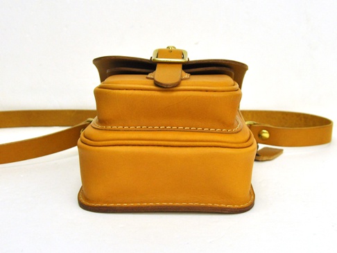 職人手作皮革皮扣直式單肩包，淺棕色皮革材質，具備金屬皮扣和縫線細節，附有寬版皮革背帶。