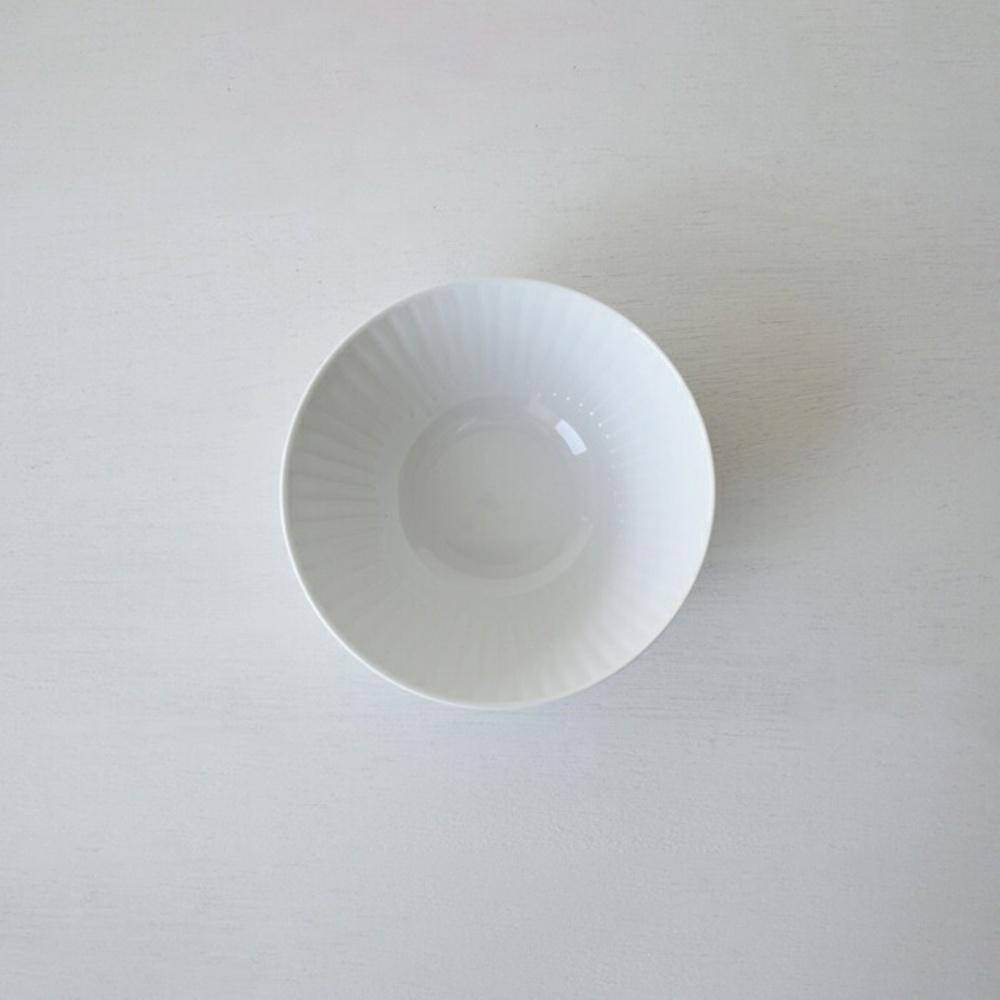 一個白色的陶瓷碗，碗身有放射狀的紋路，碗底光滑。