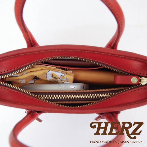 紅色皮革手提包，內部裝有手機、錢包和黃色印花布料。