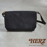 黑色皮革斜背包，有翻蓋設計，配有金屬扣環和可調節背帶。