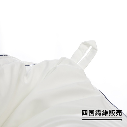 白色的被子局部特寫，有一條掛繩，右下角有「四國纖維販賣」的文字。