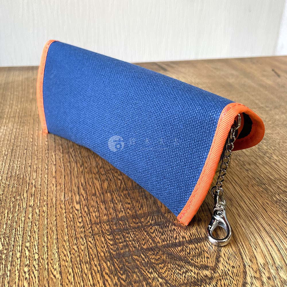 犬印鞄製作所純綿帆布眼鏡收納盒，藍色外觀搭配橘色滾邊，附有金屬扣環鏈條。