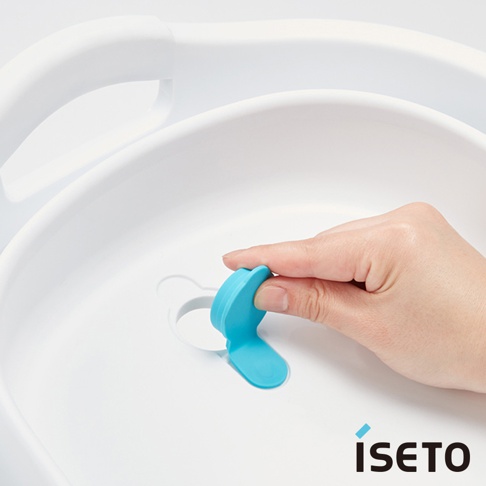 白色伸縮提籃，有淺藍色可開合式排水塞，手部正在操作排水塞。