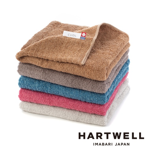 堆疊的 CUOL 今治柔彈低摩擦美髮半浴巾，展示棕褐色、灰色、藍色、粉紅色和淺灰色等顏色，材質觸感柔軟。